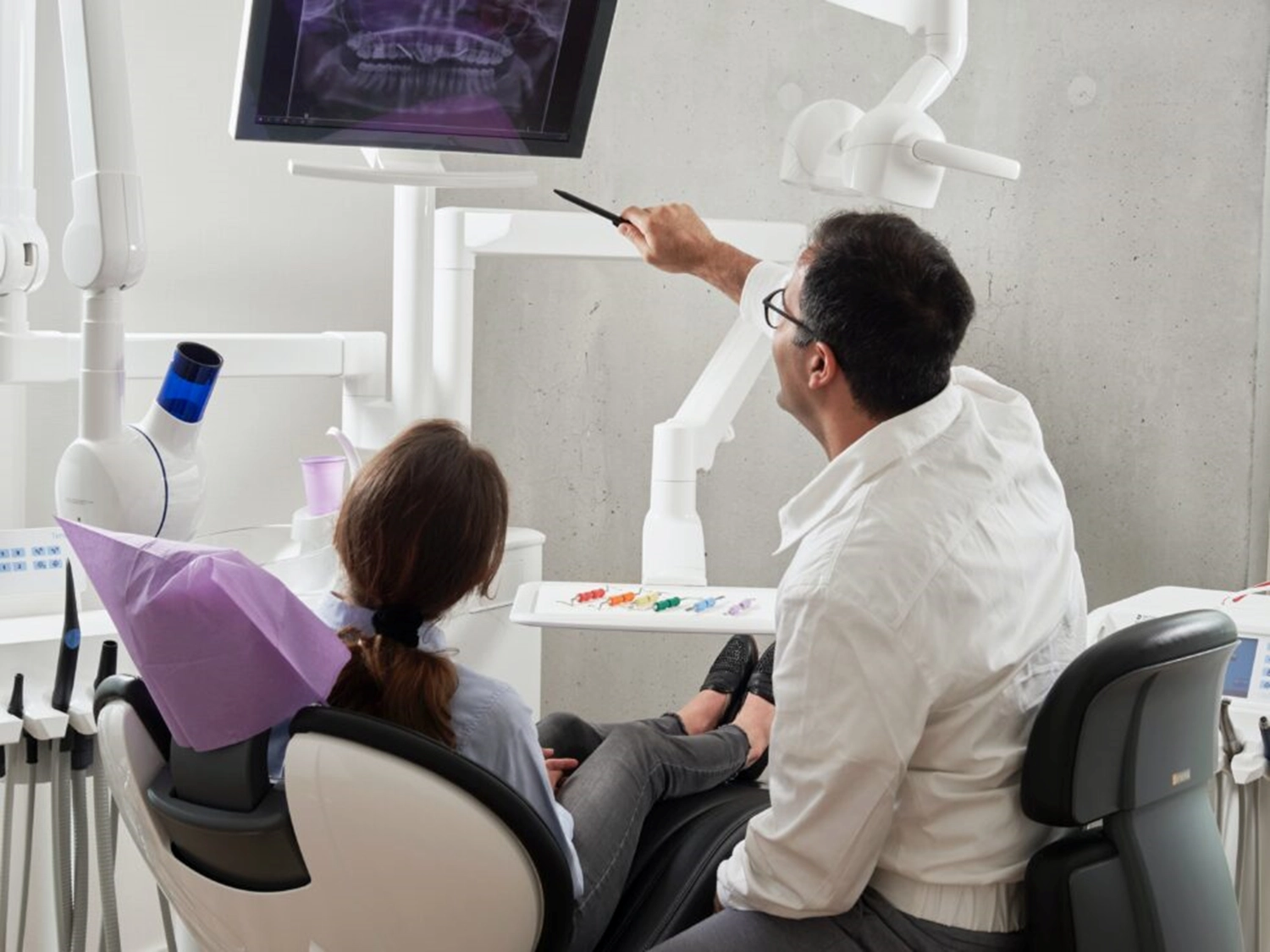A Dentist and woman reviewing an x-ray in an exam room.